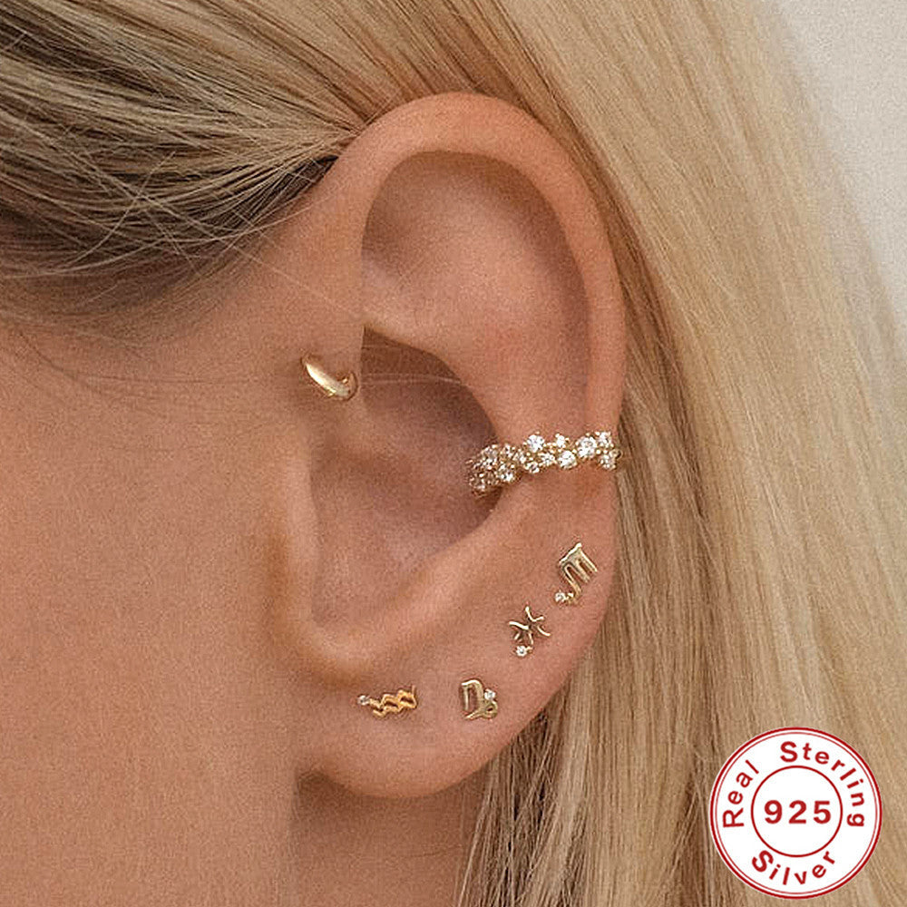 Close-up of ears adorned with various hoops and huggies, featuring Sterling Silver Constellation Earrings