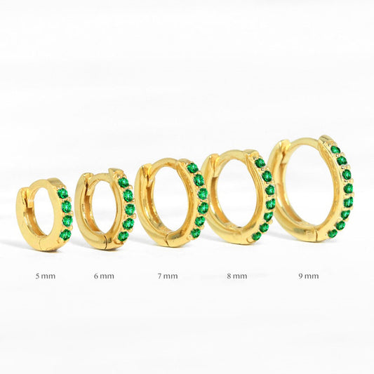 Assorted sizes of gold huggie earrings with green stones, perfect for everyday wear and styling